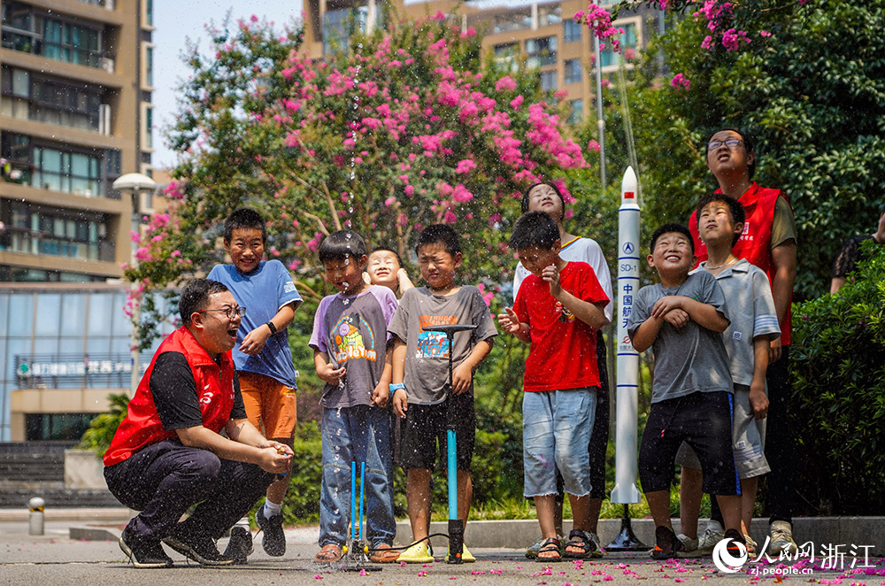 來自寧波天文愛好者協會的“甬愛幫幫團”志愿者郭皓和“小候鳥”們一起發射“水火箭”。人民網 章勇濤攝