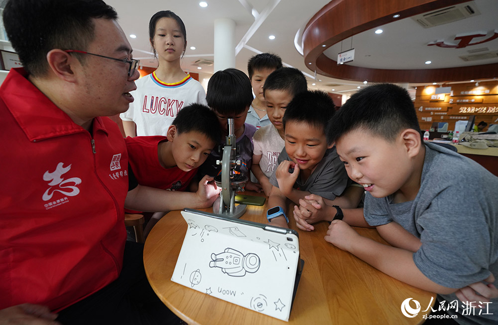 來自寧波天文愛好者協會的“甬愛幫幫團”志愿者郭皓在向“小候鳥”們普及天文航天知識。人民網 章勇濤攝