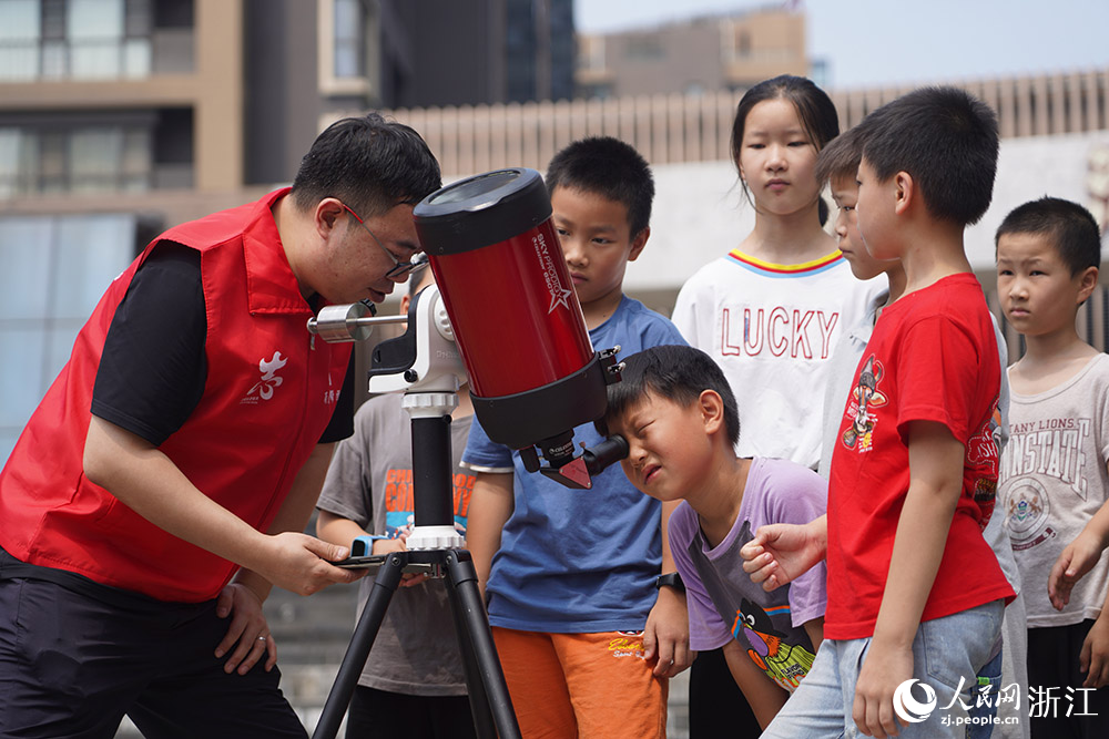 來自寧波天文愛好者協會的“甬愛幫幫團”志愿者郭皓帶領“小候鳥”們觀察太陽黑子。人民網 章勇濤攝