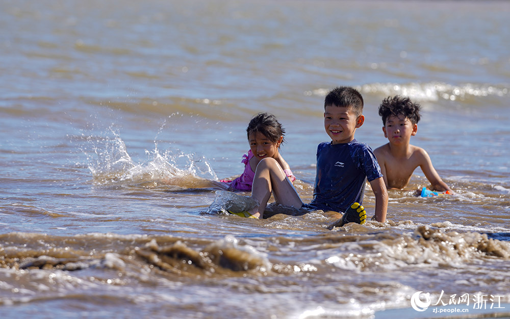 在舟山市岱山縣秀山島，游客盡情地踏浪戲水，欣賞美景。人民網 章勇濤攝