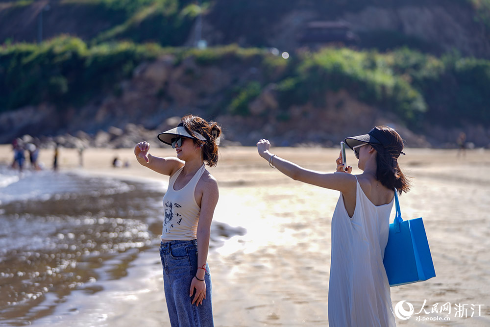 在舟山市岱山縣秀山島，游客盡情地踏浪戲水，欣賞美景。人民網 章勇濤攝