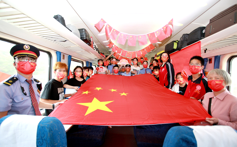 列車員與旅客手托國旗合影留念。沈克勤攝