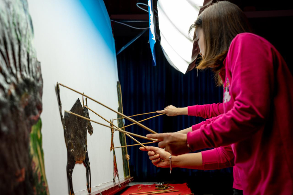 皮影藝人站在幕布后進行表演。周壽根攝