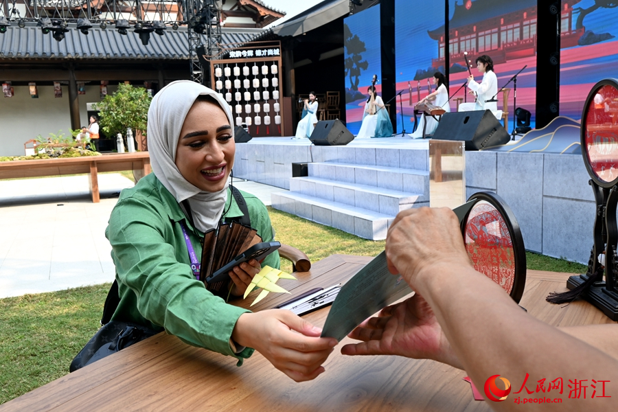 亞奧理事會代表欣喜地接過現場定制版的人像剪紙。人民網記者 張麗瑋攝