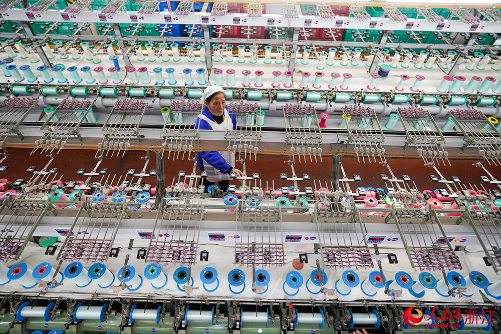 浙江省紹興市新昌縣達利絲綢智能工廠內一派繁忙，工人在生產線上趕制訂單。人民網 章勇濤攝