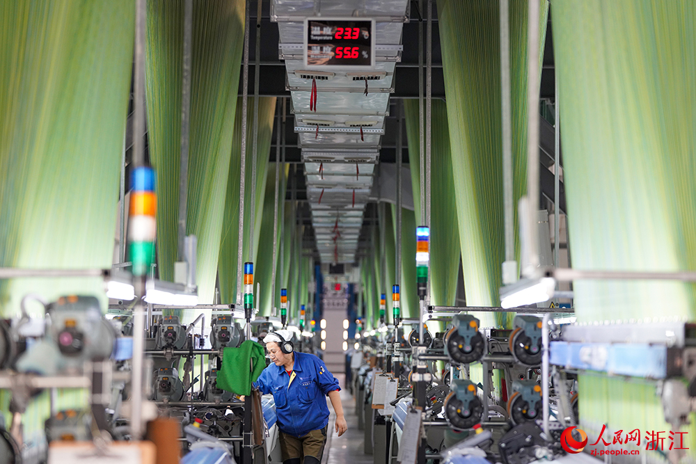 浙江省紹興市新昌縣達利絲綢智能工廠內一派繁忙，工人在生產線上趕制訂單。人民網 章勇濤攝