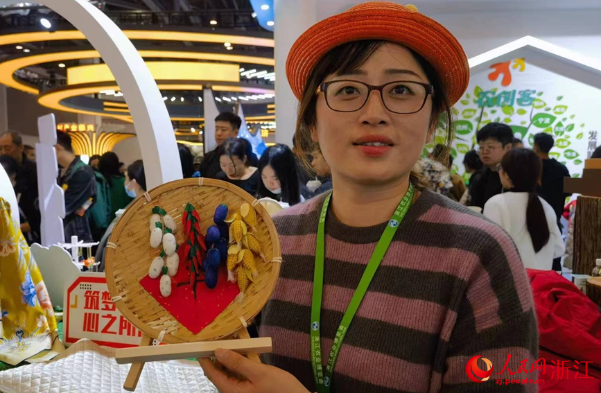 金肖黎向記者介紹由蠶繭制作的“豐收圖”。人民網記者 張帆攝