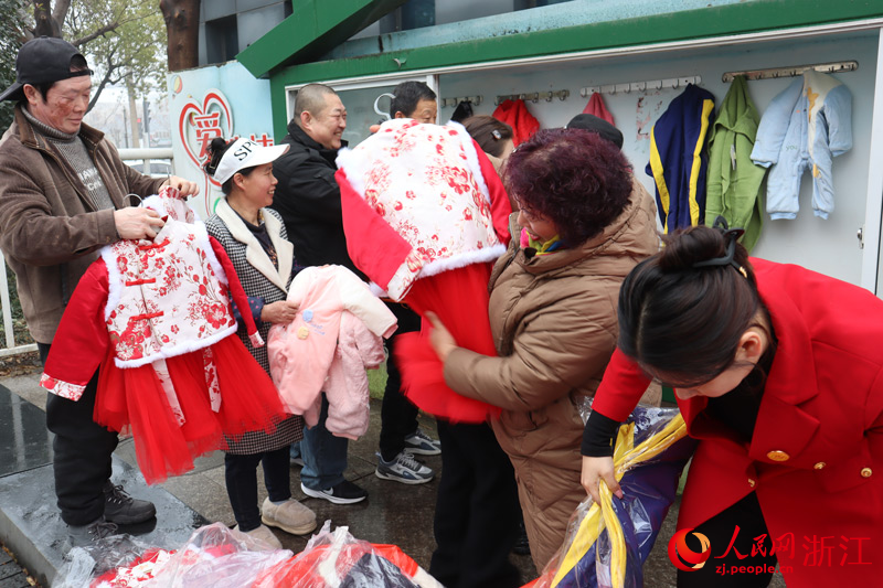 周邊居民聚集在志愿者身邊，滿心歡喜地領取童裝。人民網 孫鵬攝