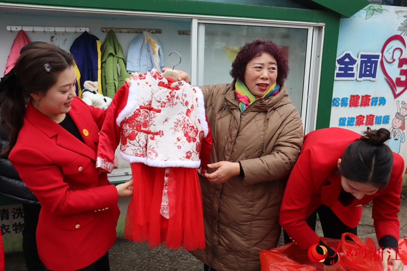 周邊居民聚集在志愿者身邊，滿心歡喜地領取童裝。人民網 孫鵬攝