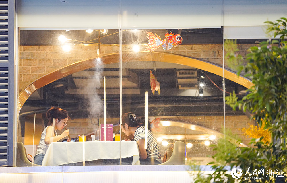 5月25日，杭州武林夜市，游客正在沿街店鋪用餐，翻騰的熱氣與燈光交織，充滿煙火氣。人民網 章勇濤攝