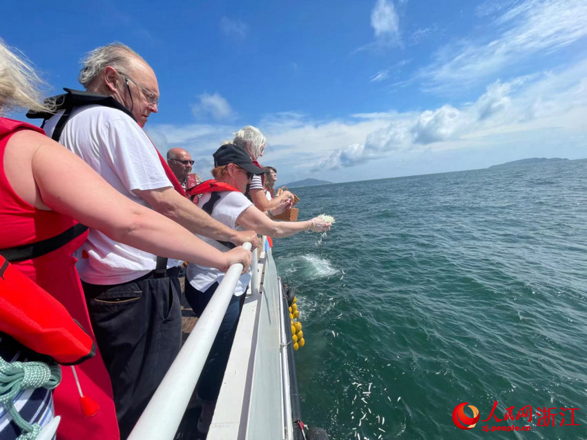 “里斯本丸”號船英軍戰俘后人將白色花瓣灑向蔚藍的大海。人民網記者 王麗瑋攝