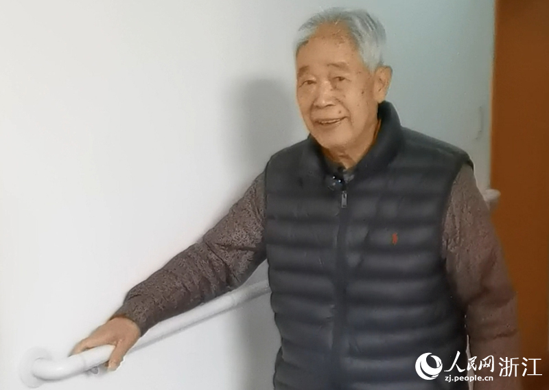 潘日華利用走廊的防滑一字扶手在家走路做康復鍛煉。人民網記者 張帆攝