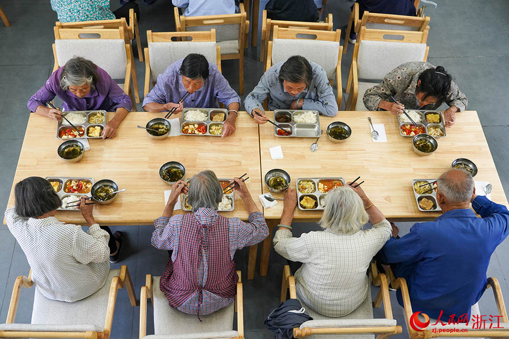 在浙江省紹興市柯橋區王壇鎮老年食堂里，飯菜飄香，老人們圍坐桌前，邊吃邊聊，其樂融融。人民網 章勇濤攝