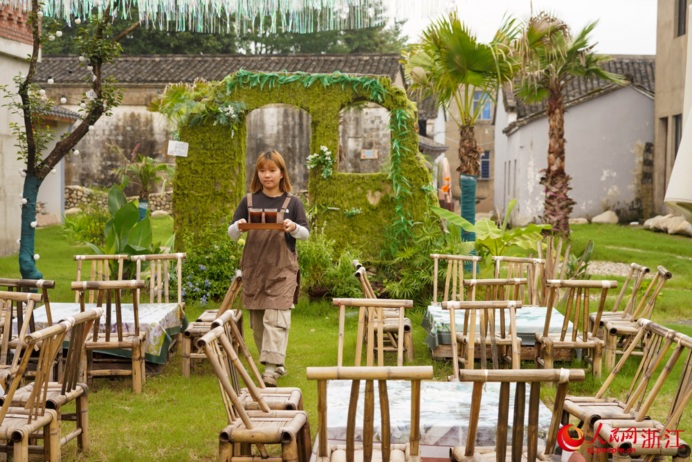 6月25日，寧波市寧?？h前童鎮官地嚴家村，工作人員在給游客送咖啡。該村通過著書、建館、AI修復，創造性打造“村咖”等文旅業態，依托項目化推進，讓老舊的村莊呈現精彩蝶變。人民網 章勇濤攝