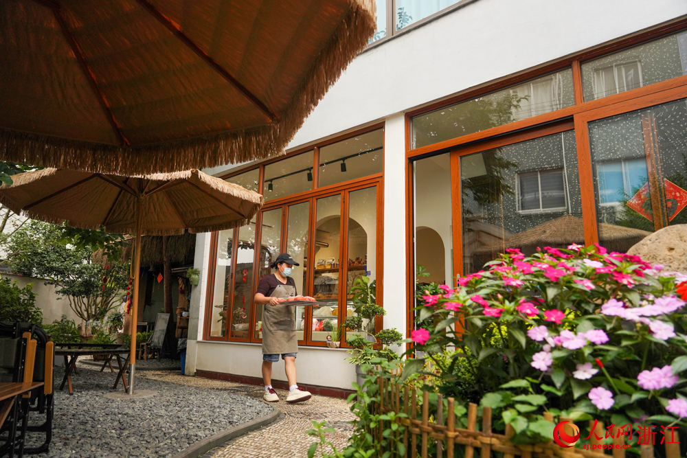 6月25日，寧波市寧?？h躍龍街道溪南劉村，工作人員在搬運剛出爐的面包。該村一處由自家老房子改建而成的庭院式面包房，已成為當地典型的小院經濟代表。人民網 章勇濤攝