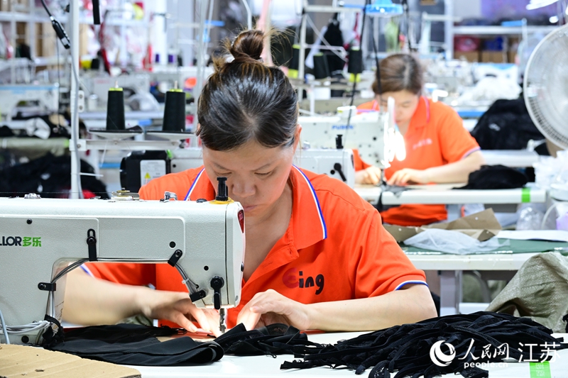 當地一家企業車間內，女工正在趕制服裝。人民網 張瀚天攝