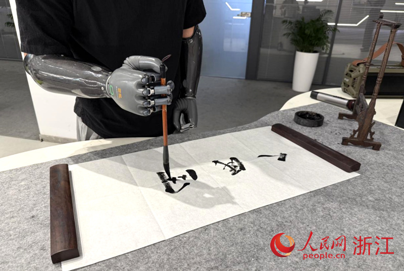 產品體驗官正在借助智能仿生手書寫毛筆字。人民網 方彭依夢攝