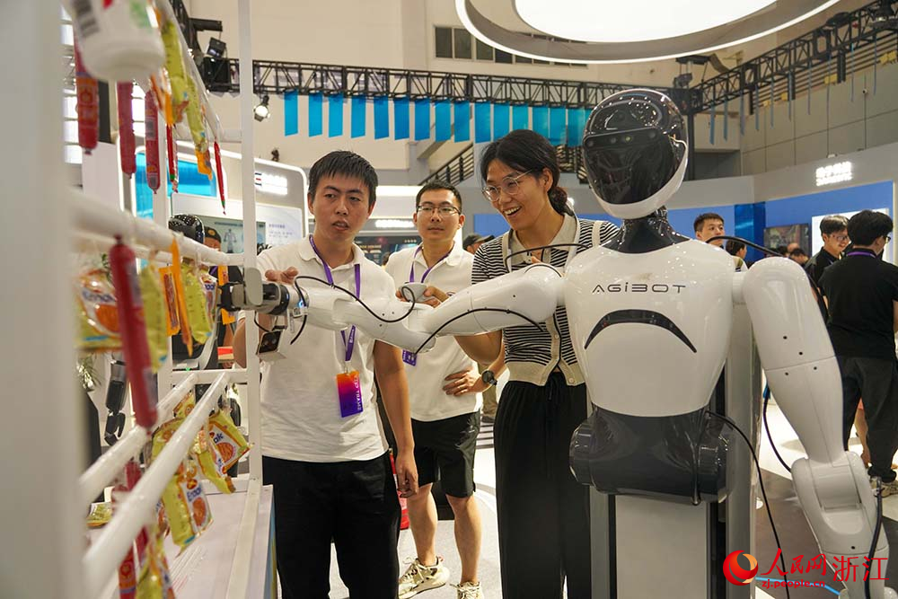 9月5日，參會人員利用人形機器人拿物件。人民網 章勇濤攝