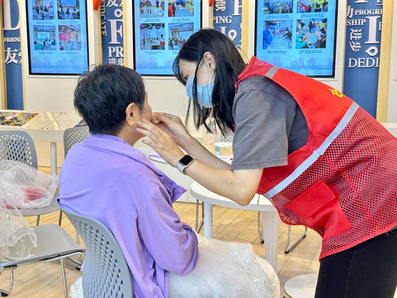 志愿者為老人化妝。劉唯攝